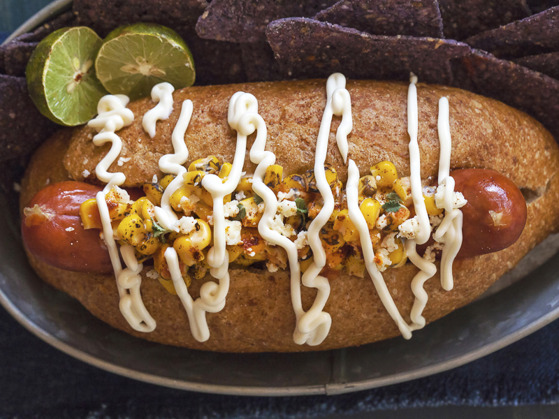 Inspired by Mexican Style Street Corn, this whole beef jumbo hot dog is topped with roasted corn, mayo, lime and spices and served in a top-cut, whole grain bolillo roll. Recipe and photo by Jackie Alpers for FoodNetwork.com