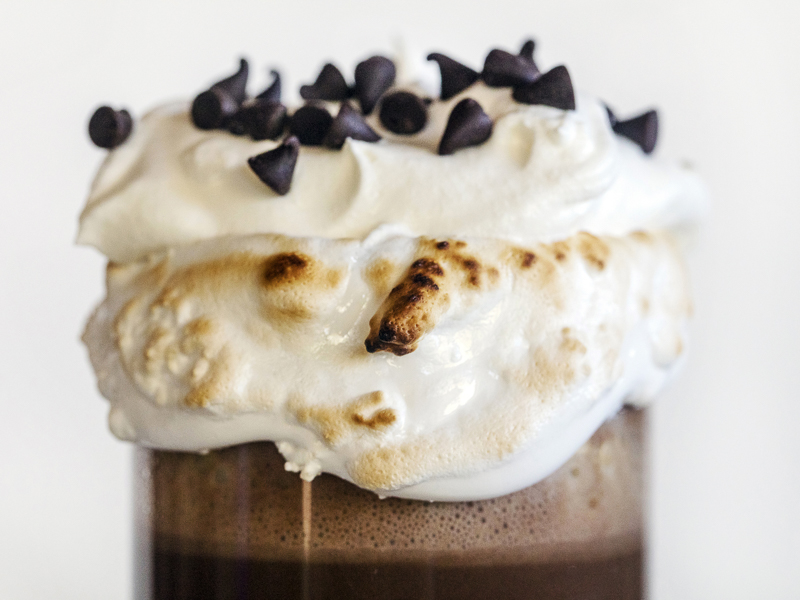 Toasted Marshmallow fluff rimming a mug of hot chocolate and topped with whpped cream and chocolate chips. 