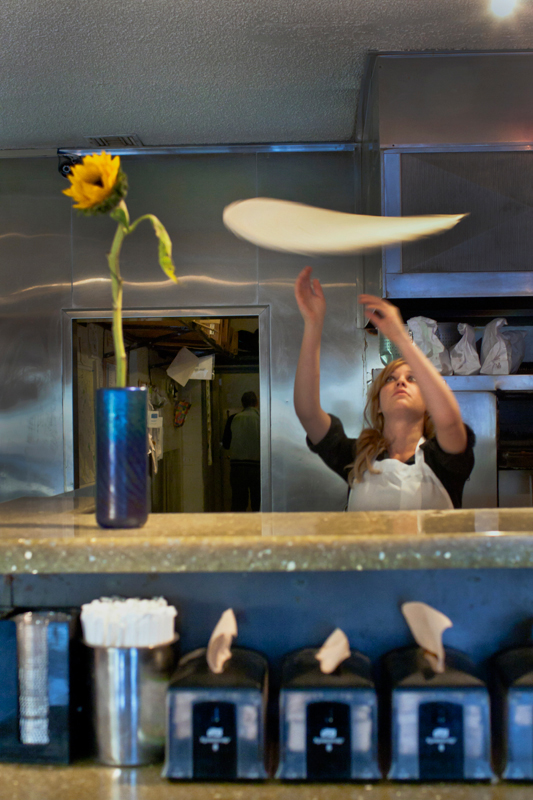 Mandi behind the counter tossing the pizza dough Pizza toss_editorial food photography by Jackie Alpers for a magazine feature article