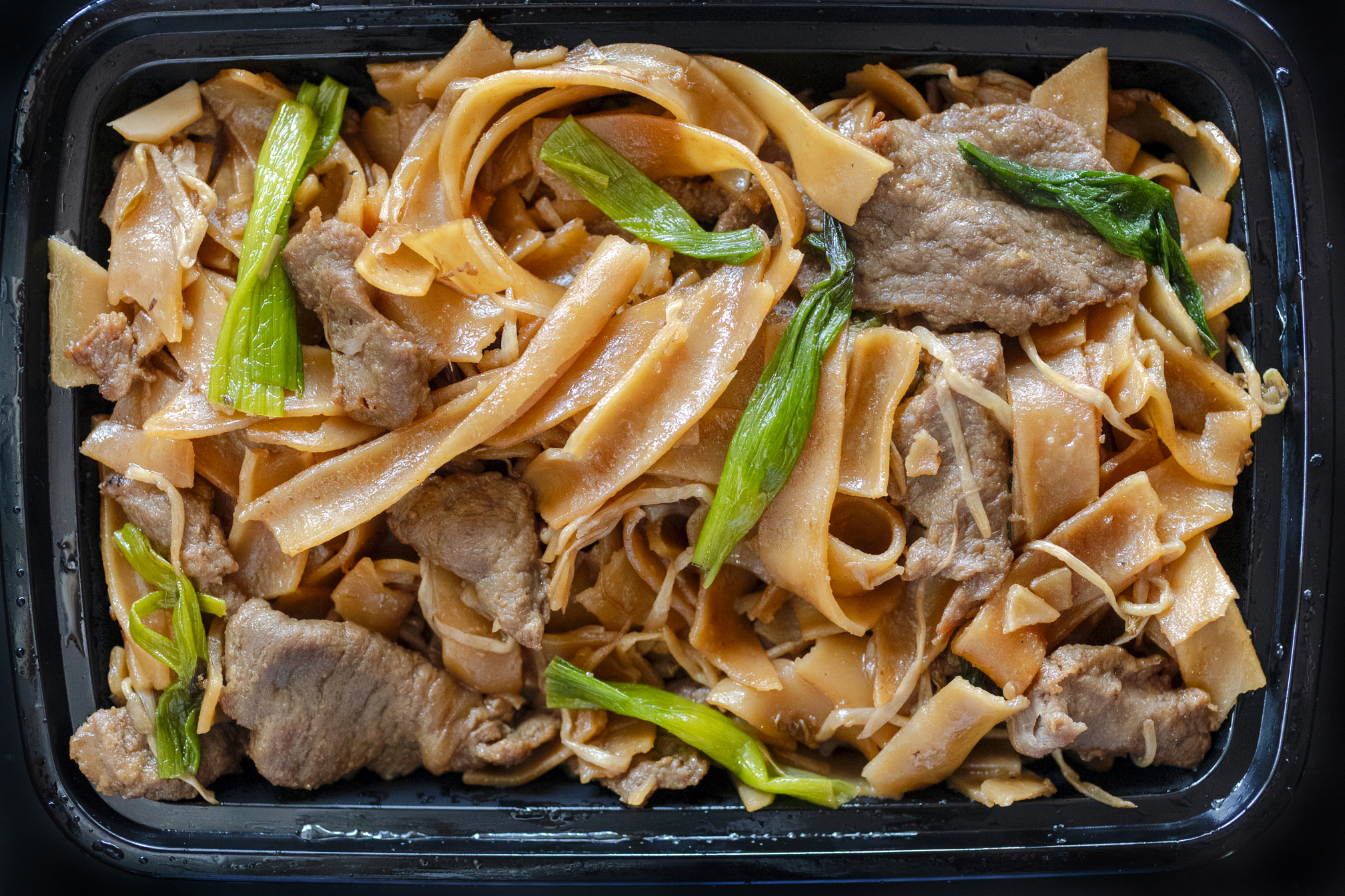 Beef Ho Fun from Asian Spice restaurant in a black takeout container. Food photography and feature article by Jackie Alpers for Discover Marana