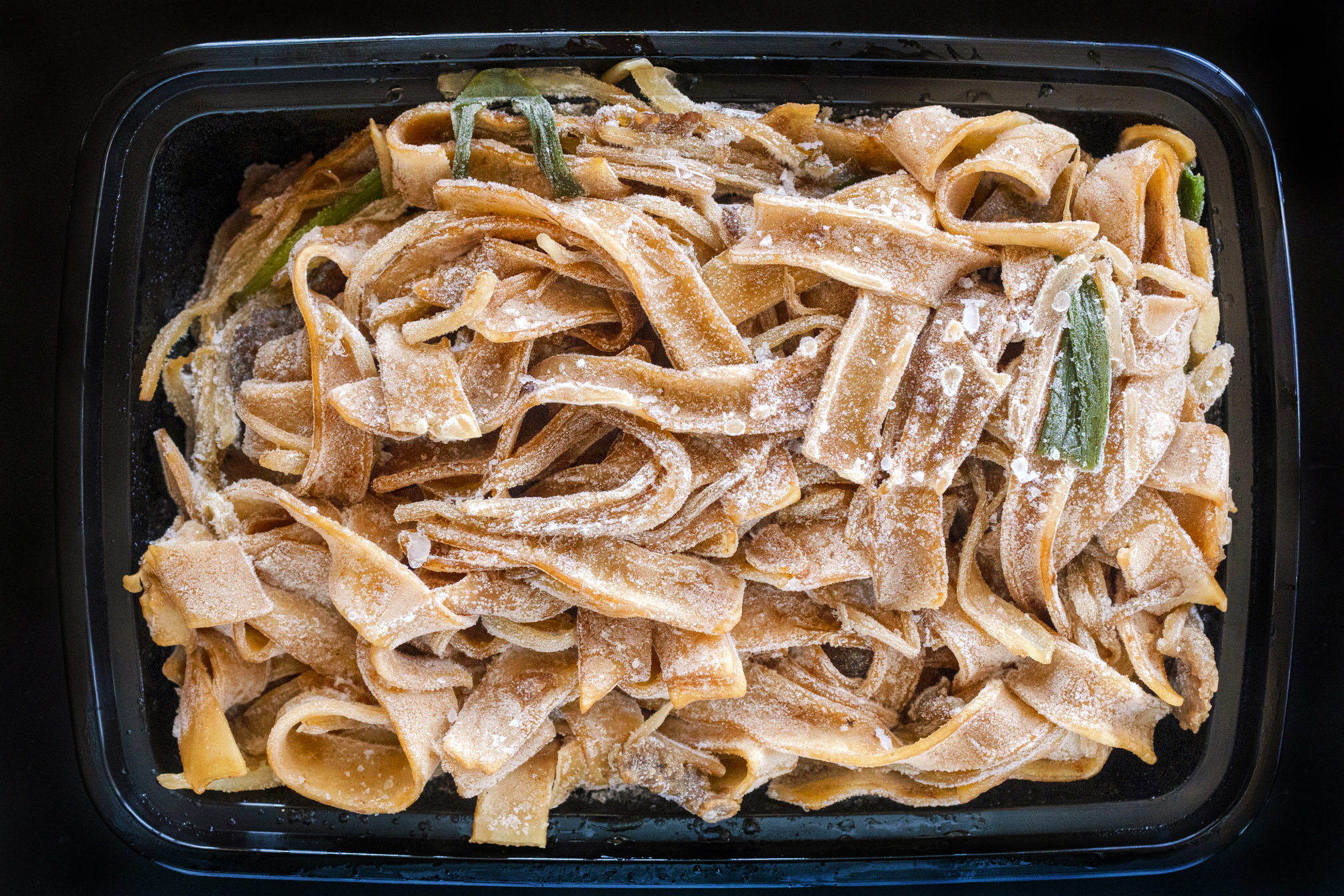 Frozen Beef Ho Fun in a black takeout container. Cantonese style Chinese food from Asian Spice can be frozen and eaten later.
